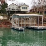 Covered boat dock with metal framing and shoreline stairs on Grand Lake in Oklahoma, shown in a residential lakefront setting