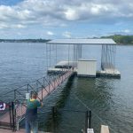 Covered boat dock with a metal roof, walkway railings, and boat lift setup on Grand Lake in Grand Lake Oklahoma