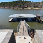 Covered multi slip dock and boat lift installation at Grand Lake Oklahoma with a floating walkway leading from the shoreline