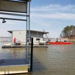 Floating dock construction project on Grand Lake Oklahoma with a covered dock structure and work barge beside the water