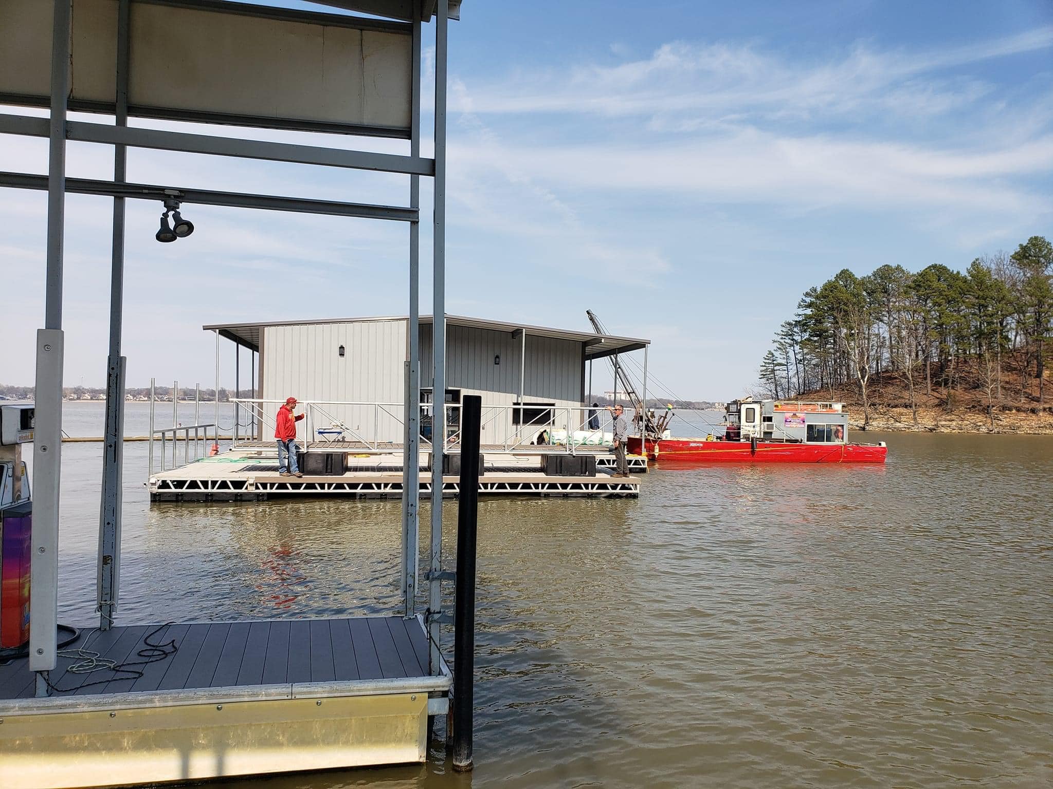 Floating dock construction project on Grand Lake Oklahoma with a covered dock structure and work barge beside the water