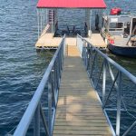 Covered boat slip and dock walkway on Grand Lake in Oklahoma with metal railings, a red roof, and a boat lift beside the water