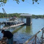 Custom dock and boat lift installation on Grand Lake in Oklahoma with a covered lift, floating walkway, and work boat at the waterfront