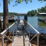 Lakefront dock walkway with white railings leading to a covered boat dock on Grand Lake in Oklahoma