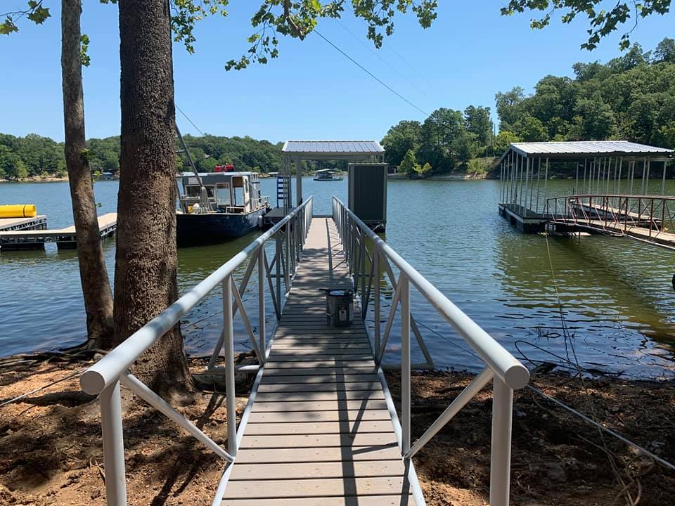 Lakefront dock walkway with white railings leading to a covered boat dock on Grand Lake in Oklahoma
