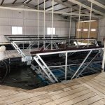 Interior view of a covered dock at Grand Lake in Oklahoma showing a boat lift installation with aluminum framing and wood dock decking