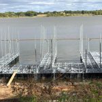Under construction multi slip dock frame on Grand Lake in Oklahoma with metal posts, floating sections, and shoreline views