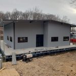 Covered boat dock building under construction on a floating dock at Grand Lake Oklahoma, featuring metal siding, a pitched roof, and lakefront access