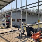 Covered boat dock construction area on Grand Lake Oklahoma with metal framing, dock decking, and workers installing a custom lakefront structure