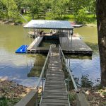 Covered multi slip boat dock with a wood walkway and handrails leading to the water at Grand Lake Oklahoma
